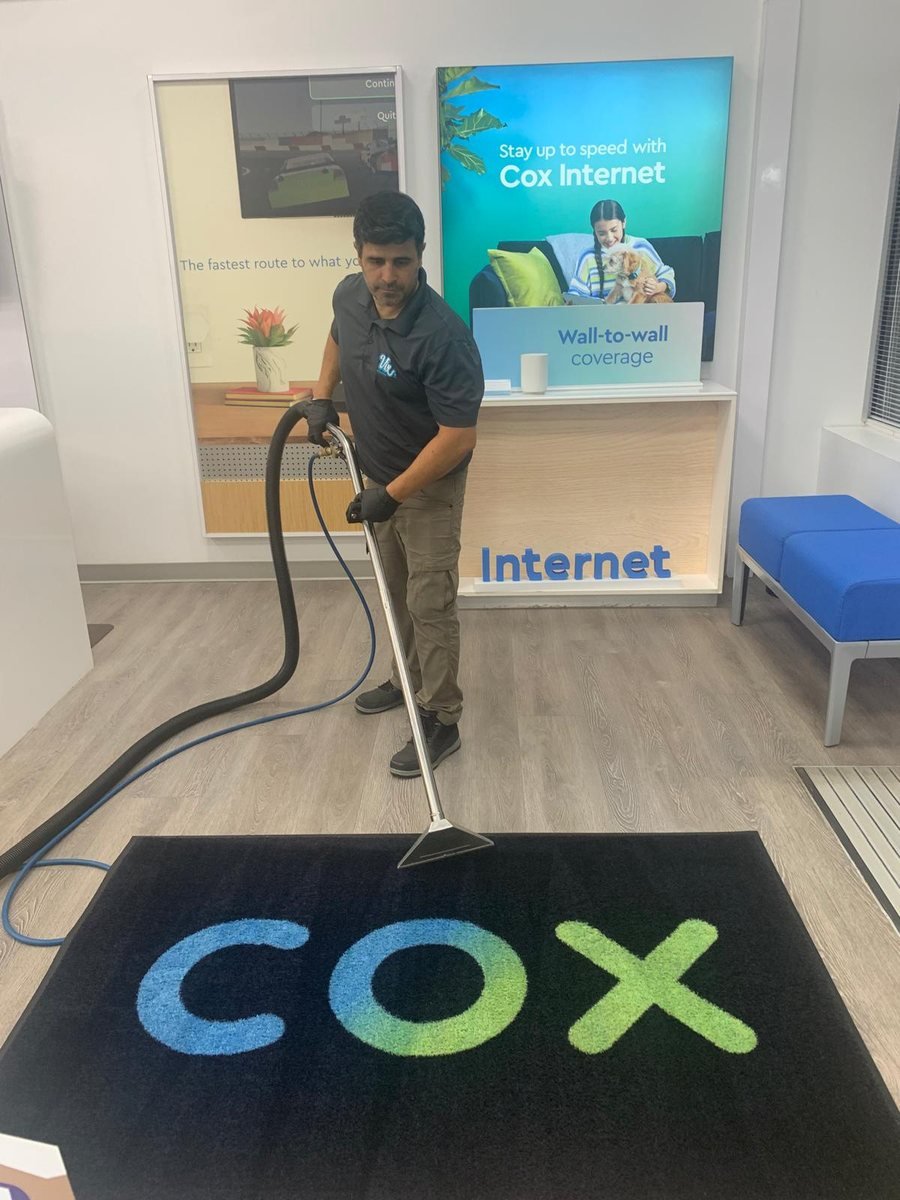Vix cleaning a branded entrance mat at a Cox Internet store