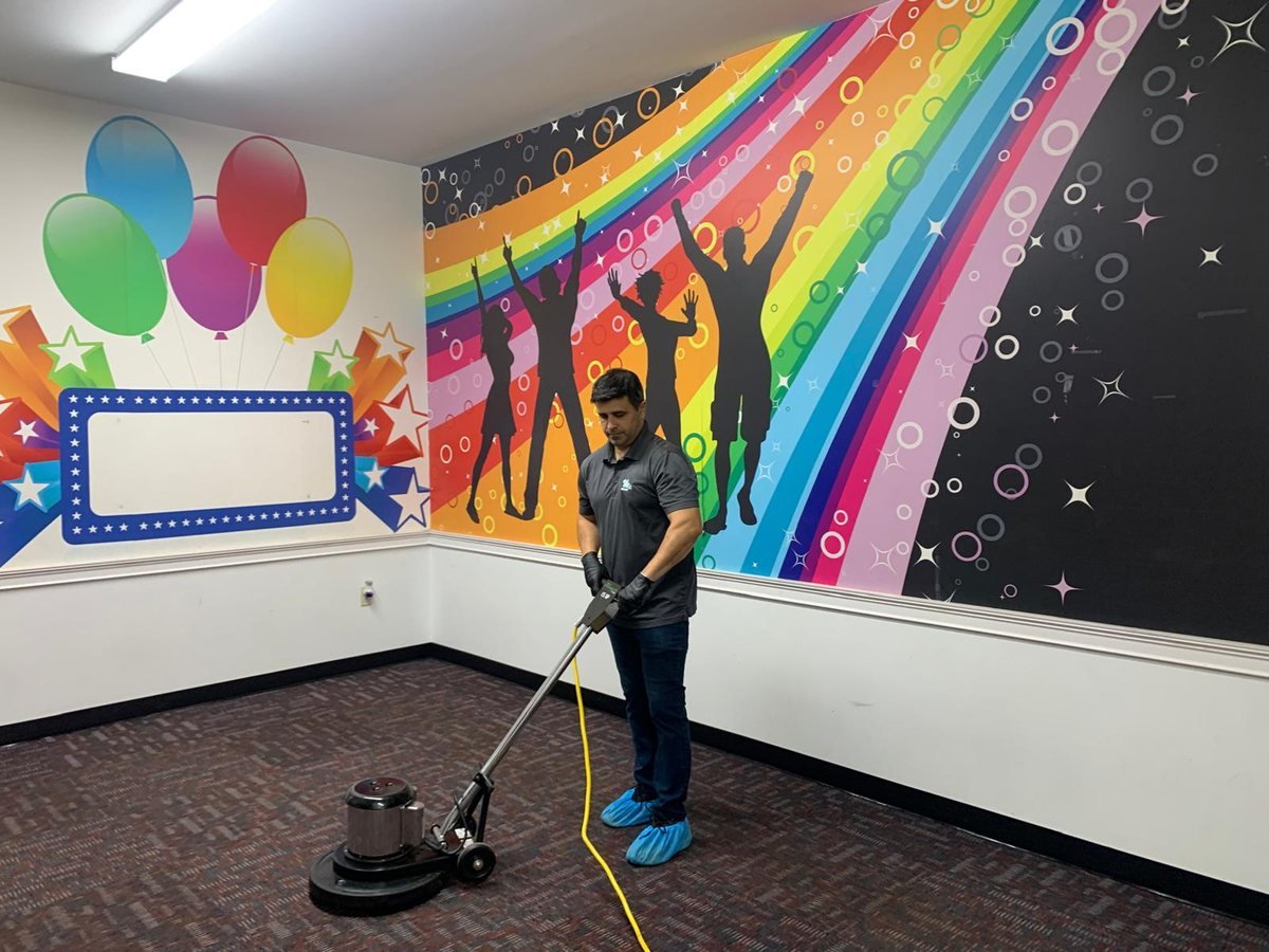 Rotary machine agitating commercial carpet in a brightly painted event room